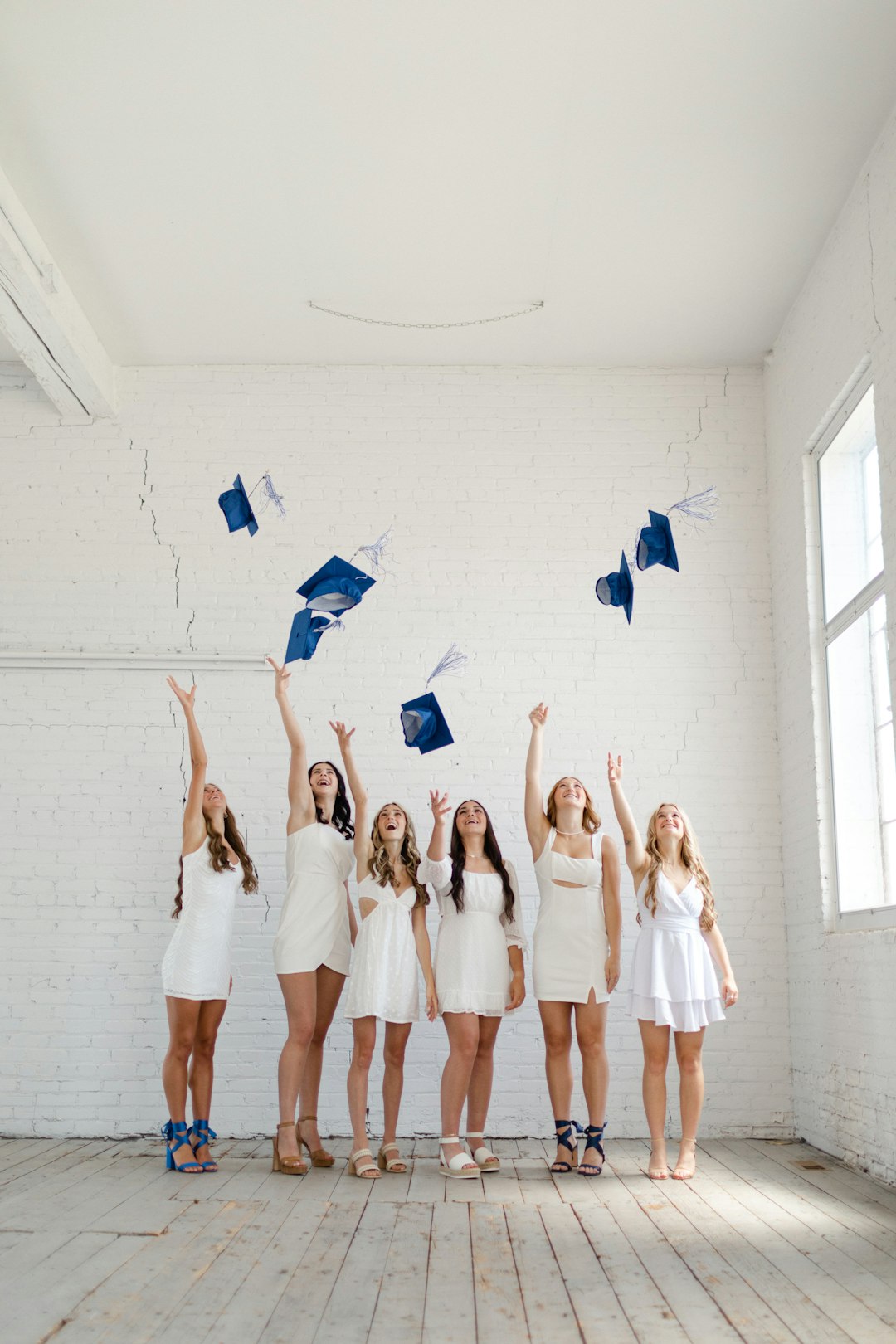 a group of young women in graduation gowns throwing their caps in the air
