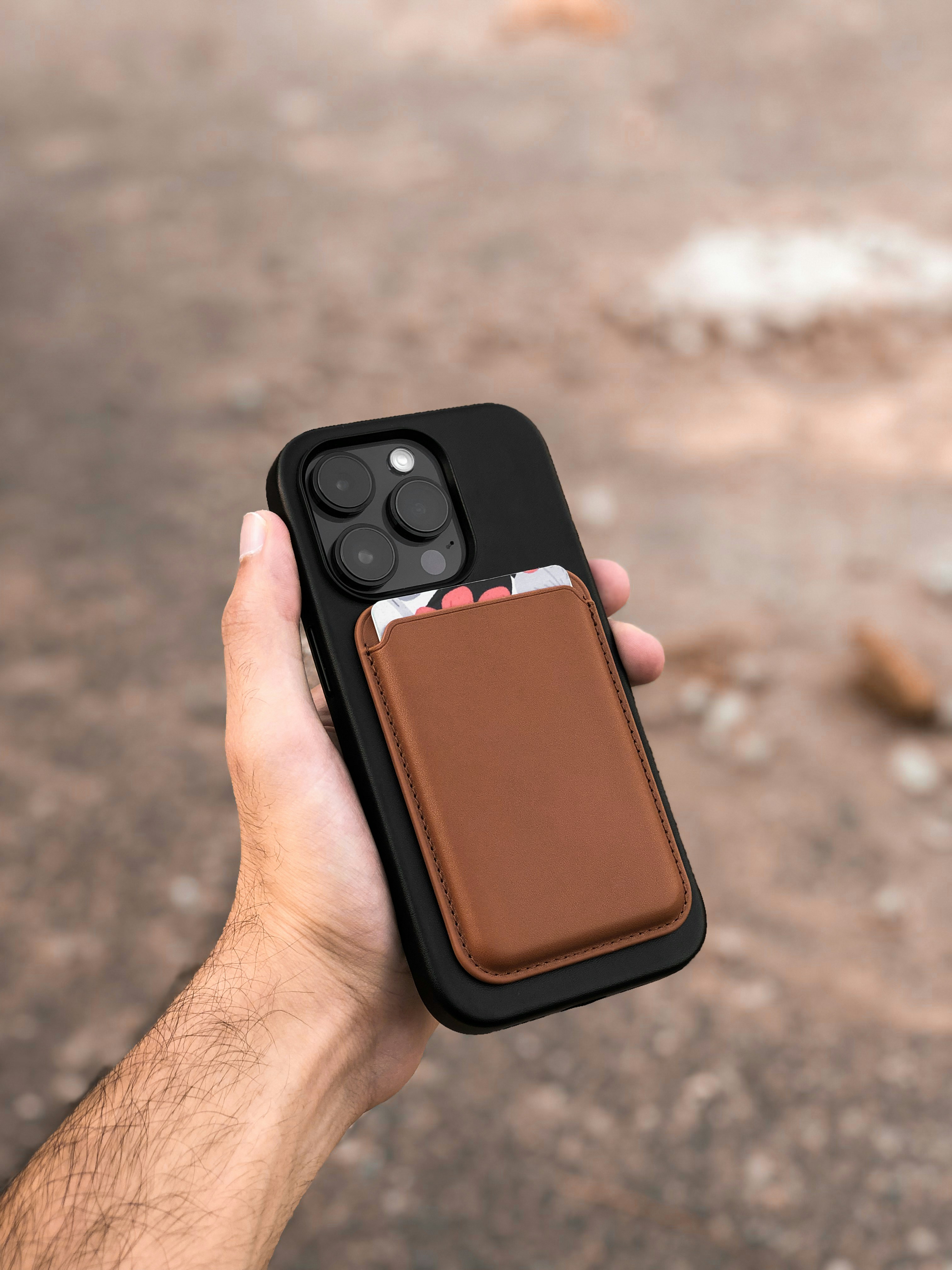 a hand holding a brown leather case for an iphone