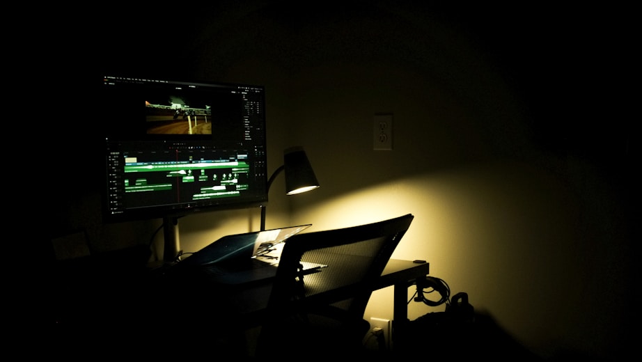 A cinematic portrait of Pedro Lucas working intently at his video editing station with dark, moody lighting.