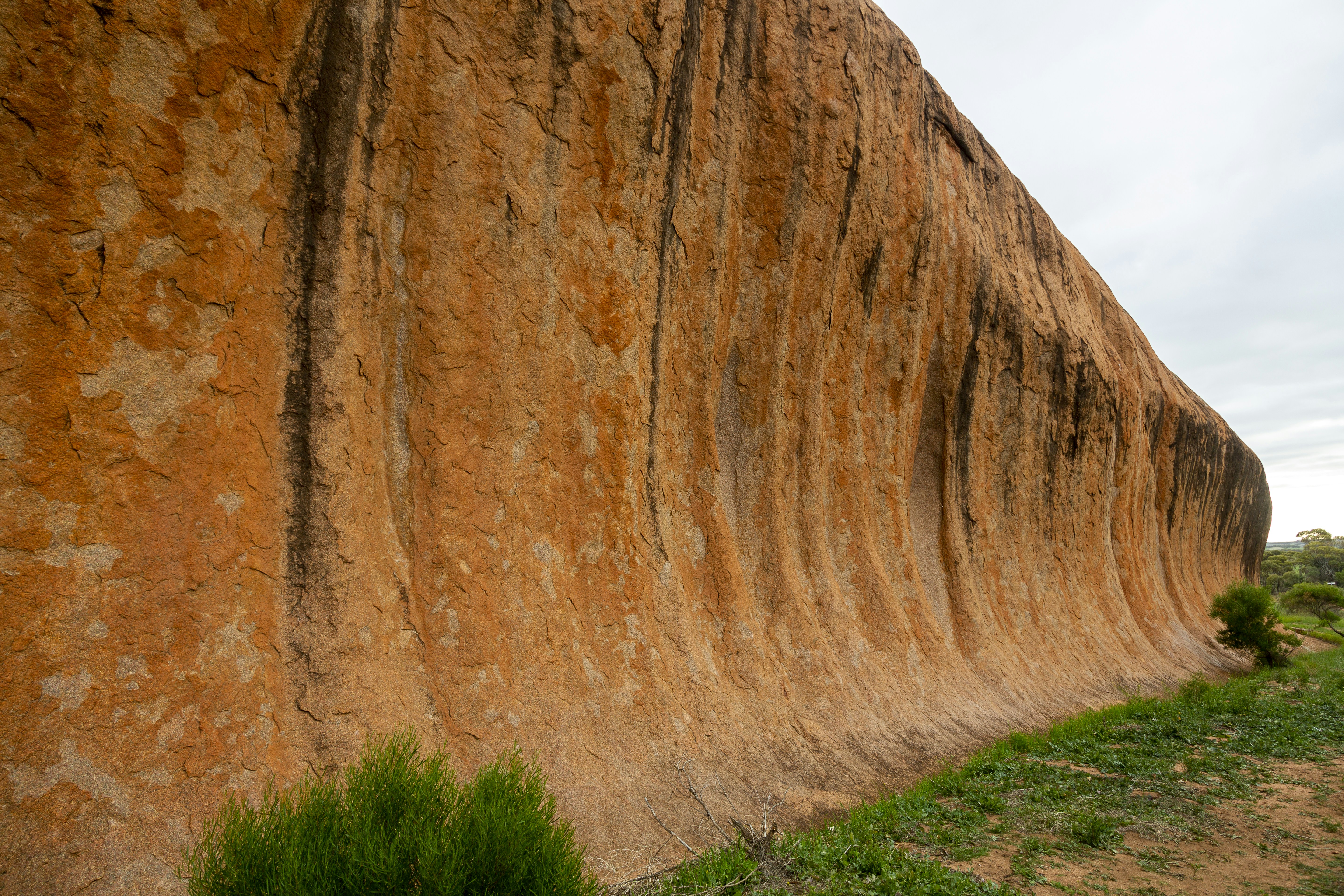 a large rock formation with grass growing in front of it