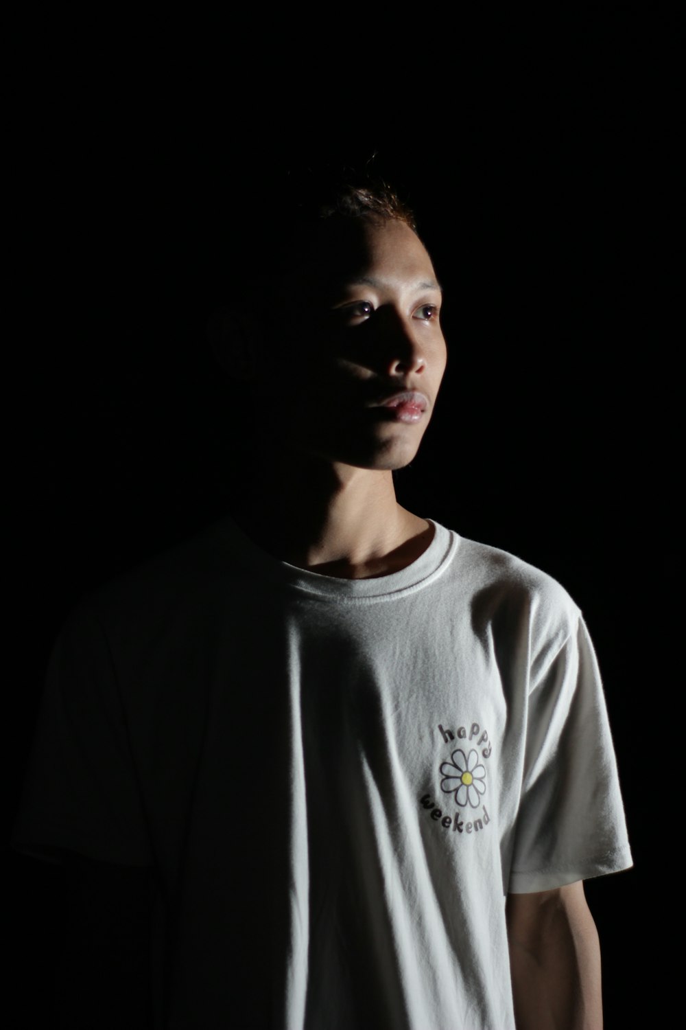 a man standing in the dark wearing a white shirt