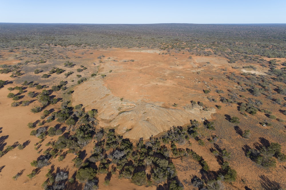 an aerial view of a dirt field with trees