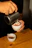 Close-up of hands pouring coffee mate into a steaming cup of coffee
