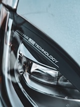 A close-up view of a car's headlight featuring 'JAGUAR LED TECHNOLOGY' branding. The image highlights the sleek and modern design of the headlight, showcasing materials like glass and metal.