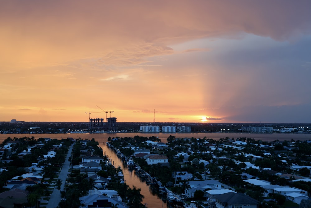 the sun is setting over a city and a body of water