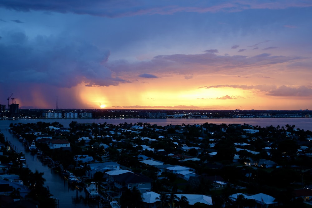 the sun is setting over a city by the water