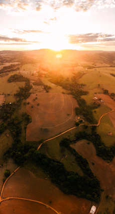 Wide view of a countryside property with a small lake, barn, and open fields at sunset