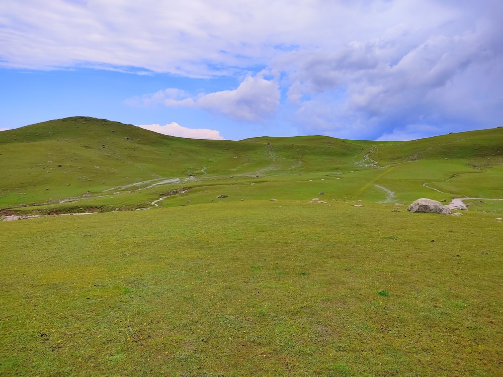 um campo gramado com uma colina ao fundo
