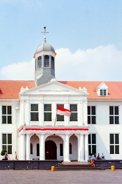 a large white building with a red and white flag