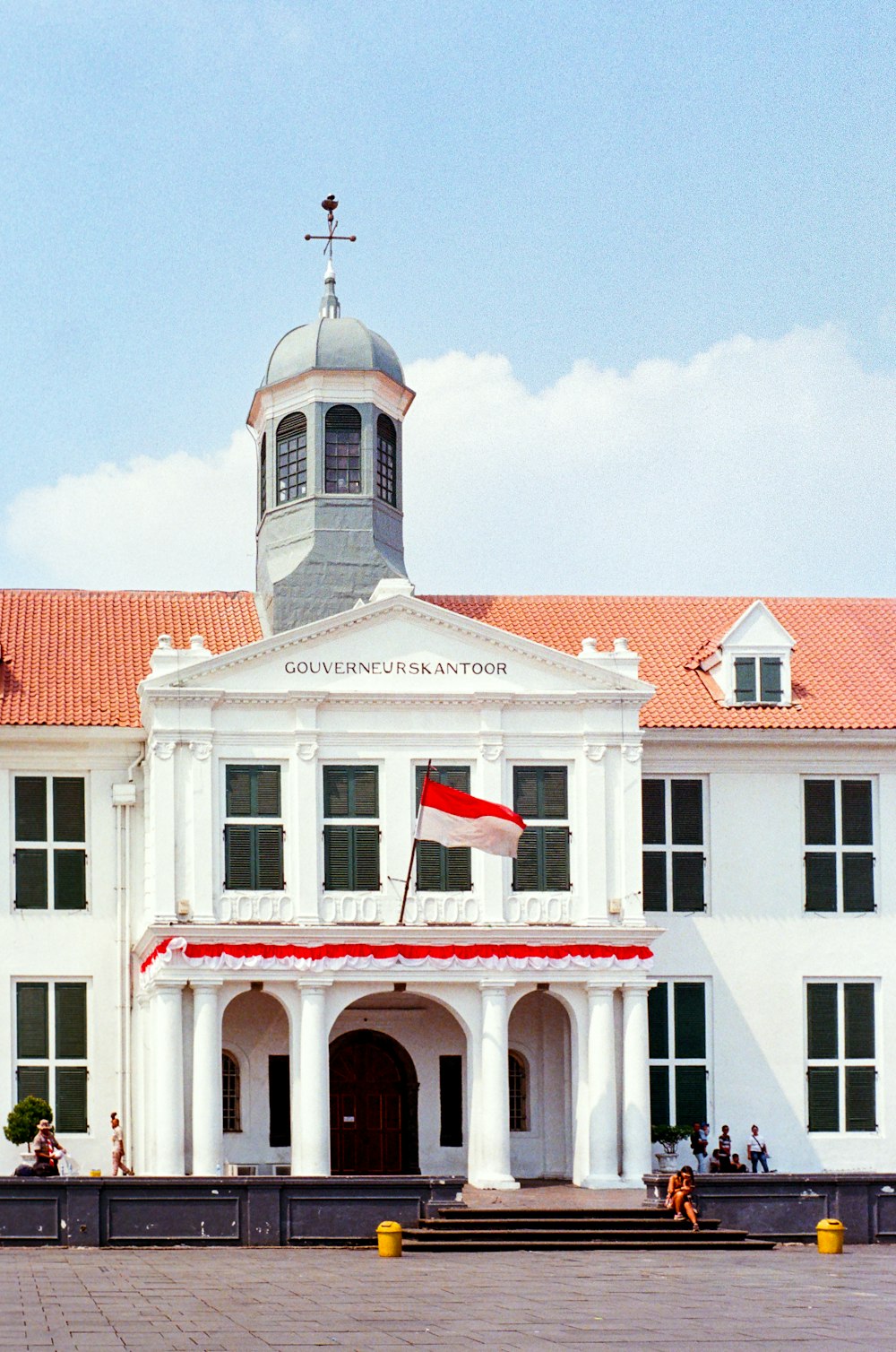 a large white building with a red and white flag