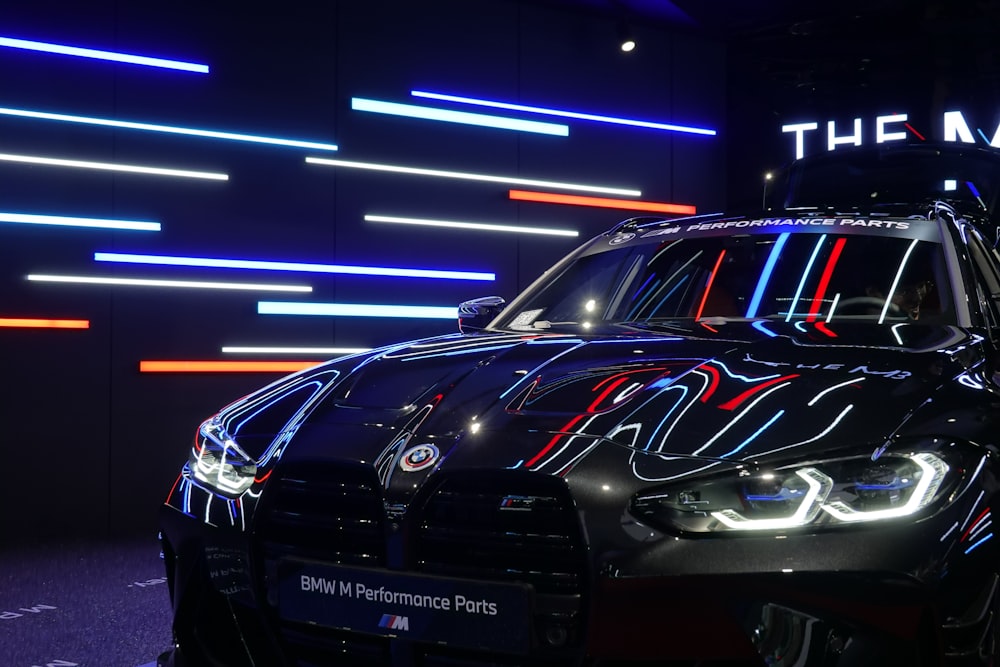 a black car parked in front of a neon sign