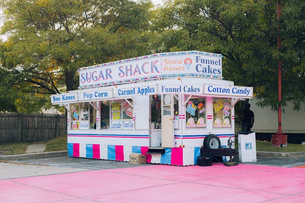 a pink, blue, and white striped food stand on the side of a road