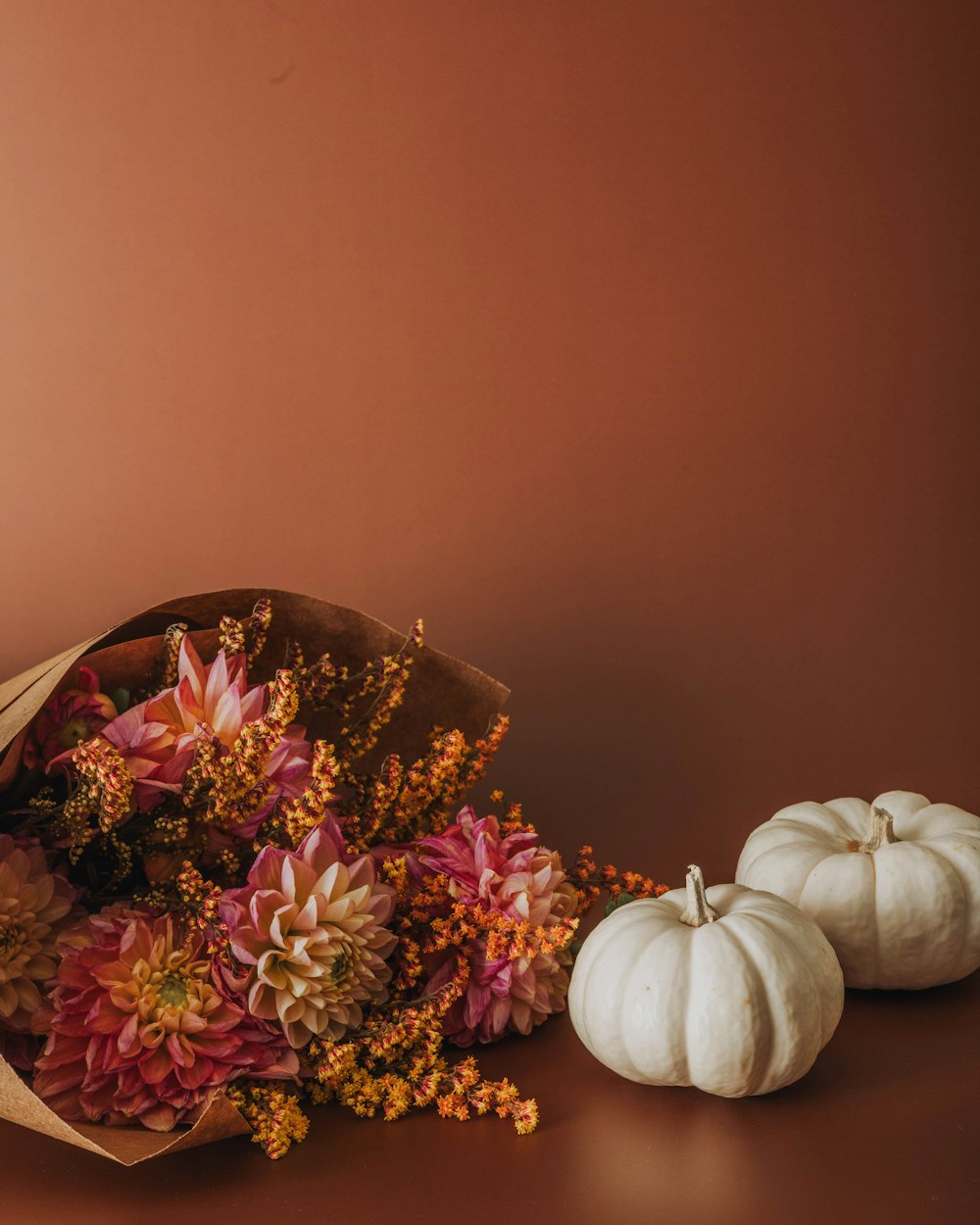a bouquet of flowers and two white pumpkins