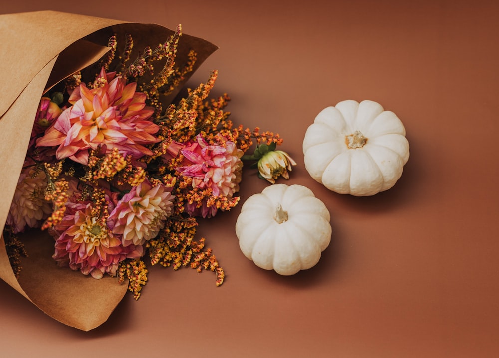 a paper bag with flowers and a white pumpkin