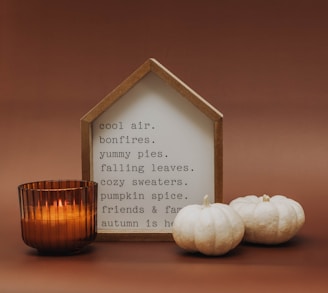 a candle and some white pumpkins on a table