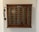 A vintage wooden telephone switchboard featuring multiple round dials with numbers and an antique telephone receiver attached to the side. The board has rows of metallic elements and numeric labels beneath each dial.