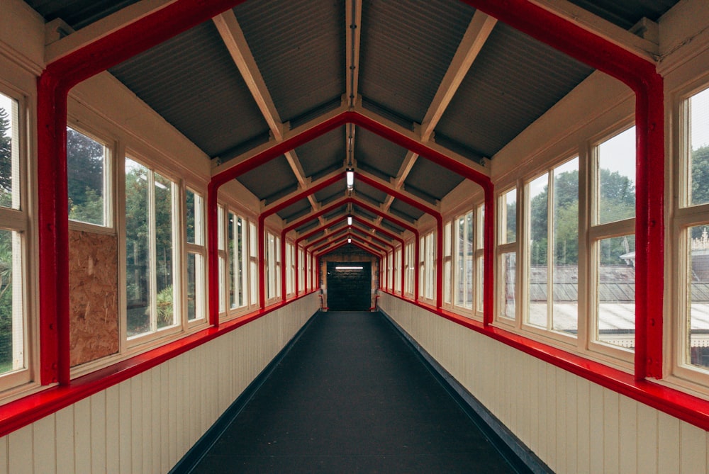 a long hallway with red and white trim and windows