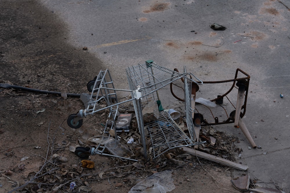 a broken shopping cart sitting on top of a pile of trash