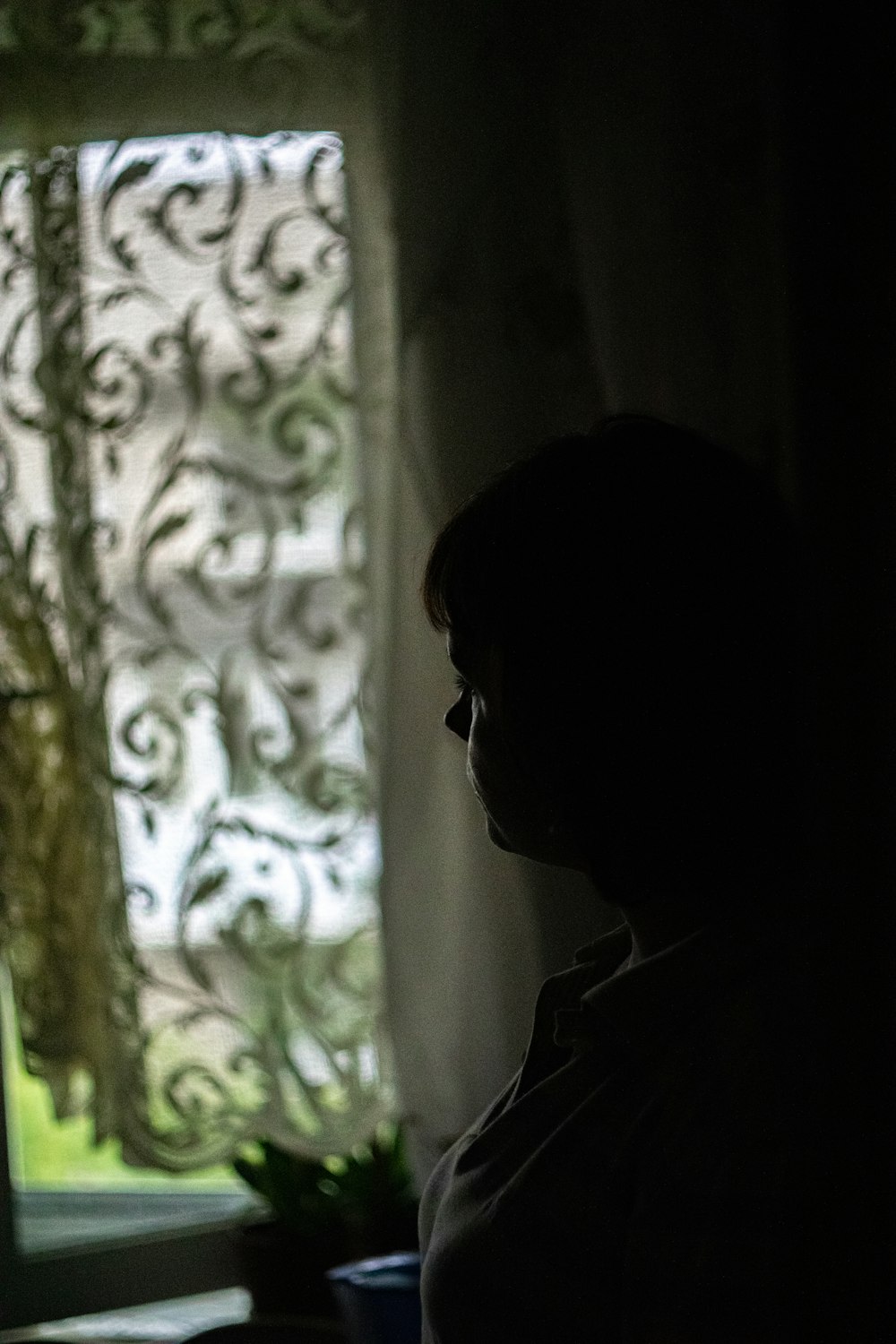 a woman sitting in front of a window in the dark