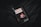 A copy of David Copperfield by Charles Dickens lies on a dark, textured fabric surface. The book cover features an illustrated portrait of a young person, with a black, white, and red color scheme. A tassel bookmark protrudes from the top of the book, adding texture and dimension.