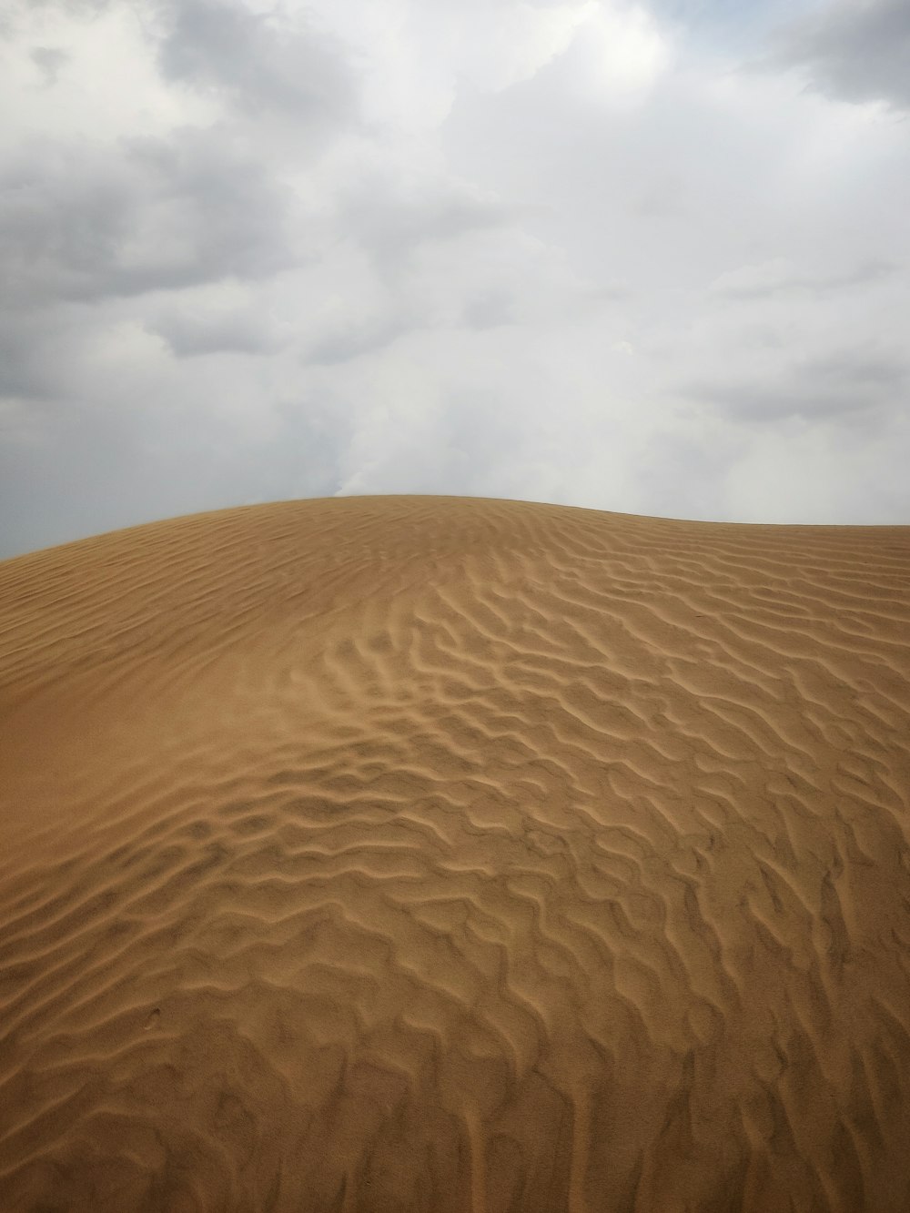 a large sand dune under a cloudy sky