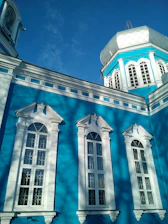 A vibrant school building with blue and violet accents under a clear sky.