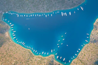 Wide shot of an inviting Aegean bay surrounded by rocky shores and anchored luxury yachts.