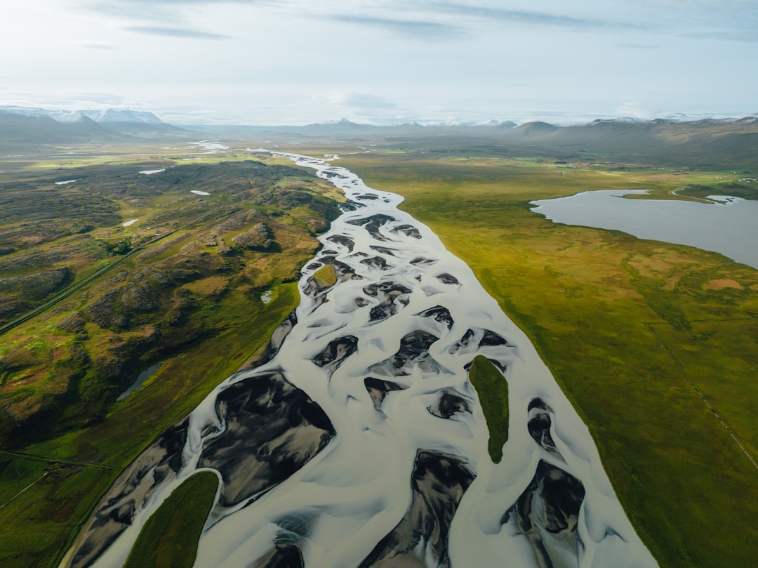 a river running through a lush green countryside,