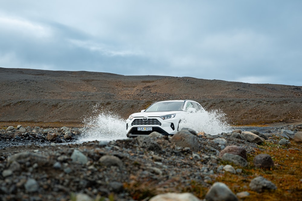 a white car driving on a rocky road