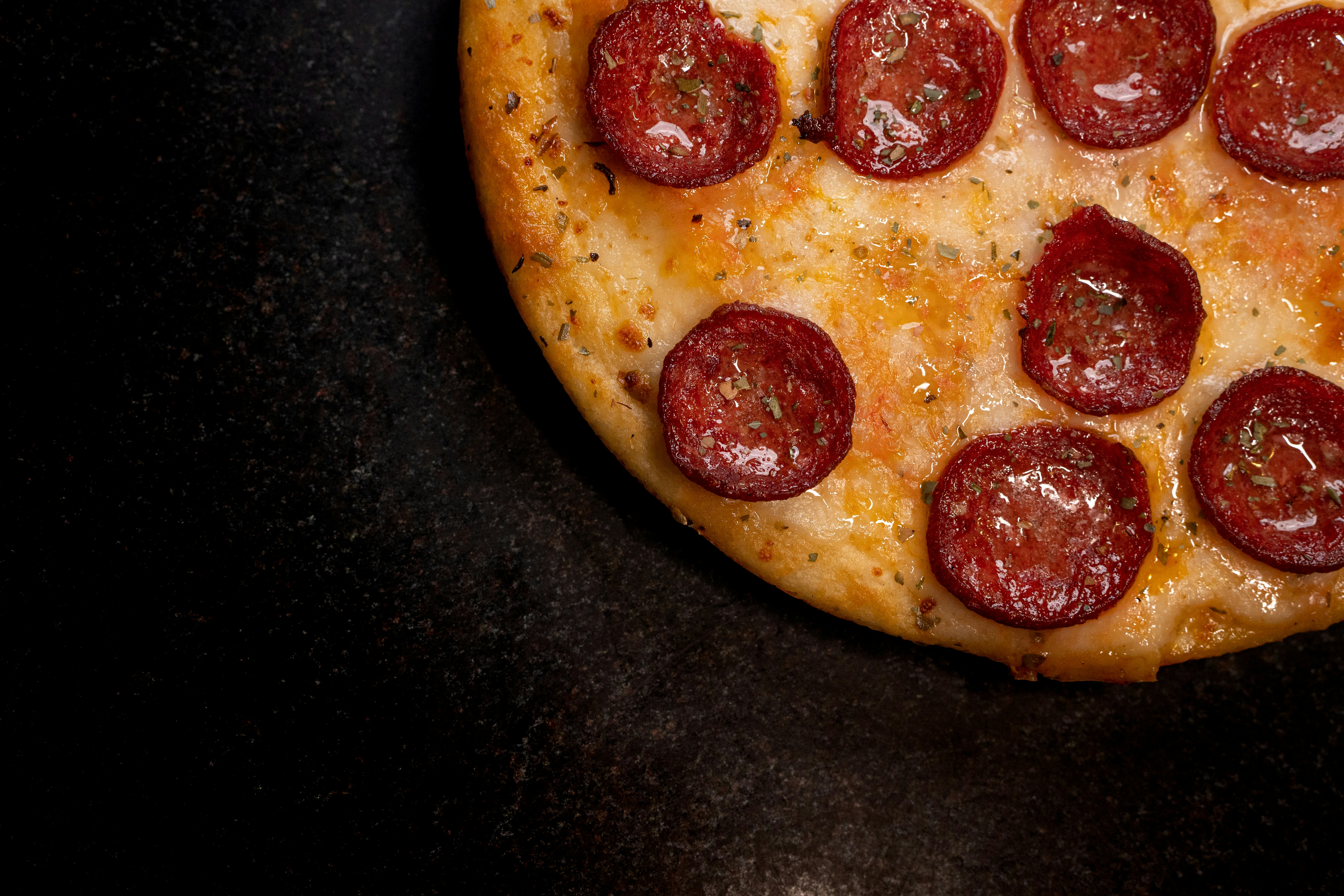 a pepperoni pizza sitting on top of a black counter
