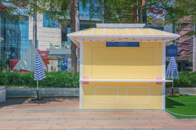 a yellow kiosk with blue and white striped umbrellas