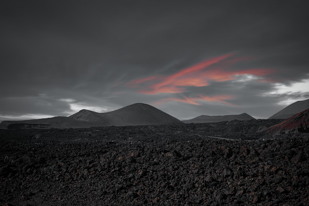 a mountain range with a red cloud in the sky,