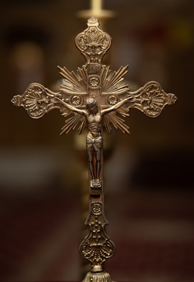 High-end artistic cross with detailed engravings against a soft, warm background.
