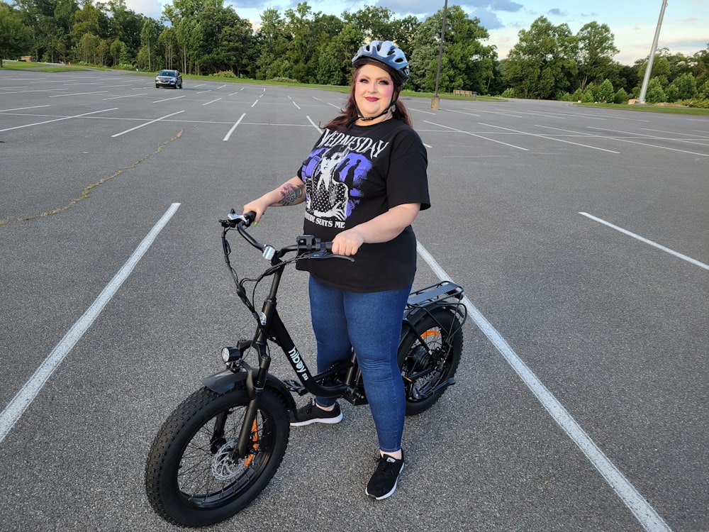 a woman standing in a parking lot with a bike