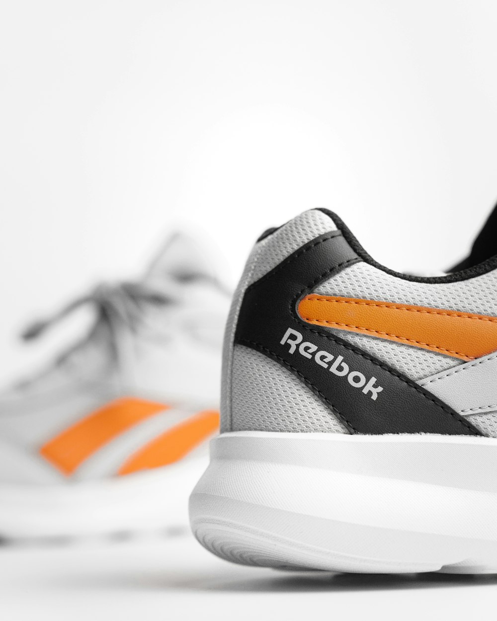 une paire de chaussures blanches et orange sur une surface blanche