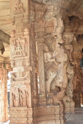 Intricate stone carvings on the pillars of an ancient structure, featuring detailed depictions of mythological figures and decorative motifs.
