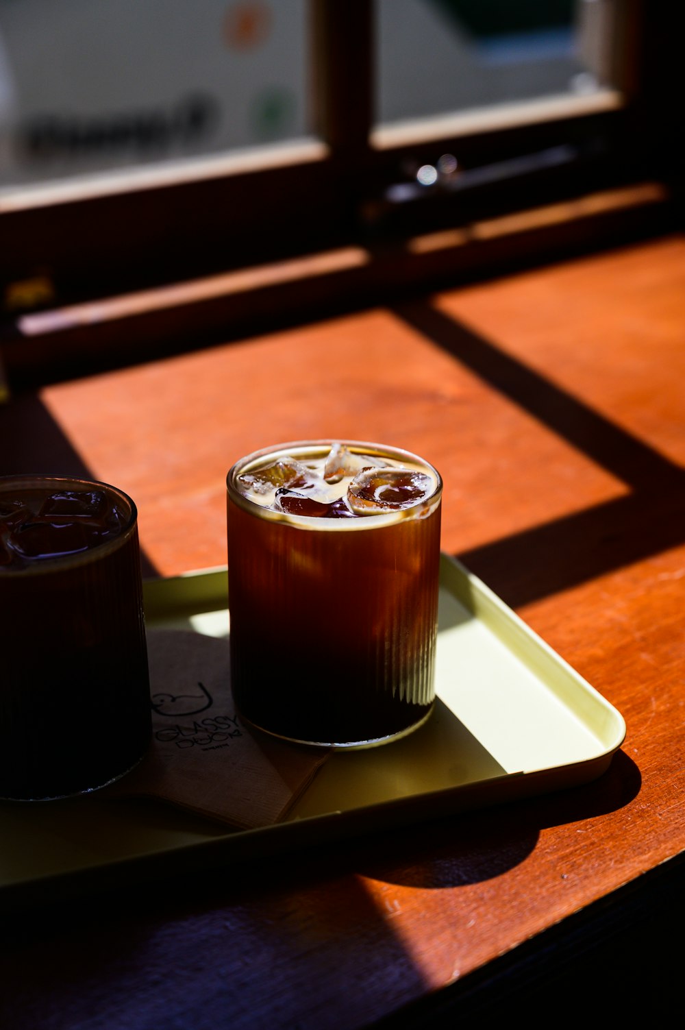 a glass of iced coffee sitting on a tray