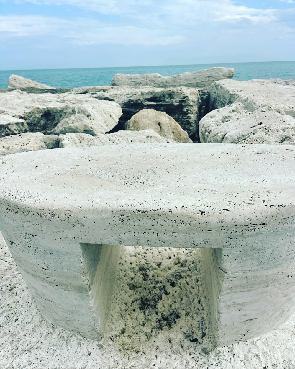 a concrete bench sitting on top of a sandy beach