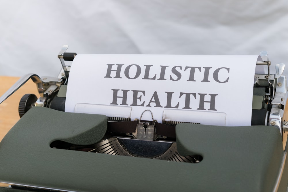 a close up of a typewriter with a paper that reads holstic health