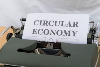 A typewriter with a piece of paper on which the words 'CIRCULAR ECONOMY' are typed. The typewriter has a classic design with a green body and visible metal components.