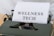 A vintage typewriter holds a sheet of paper with the words 'WELLNESS TECH' typed in large, bold letters. The typewriter is in a shade of olive green, with a focus on the metal and mechanical components. The paper is placed neatly in the roller, ready for typing more text.