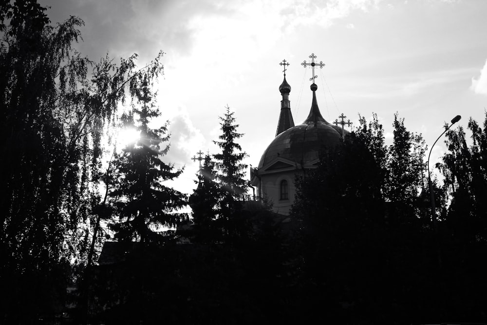 a black and white photo of a church and trees