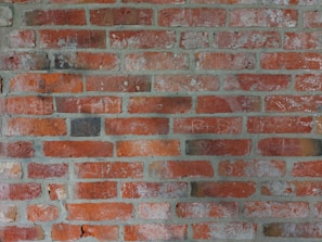 Red bricks arranged in a horizontal pattern with visible mortar between each row. The surface shows signs of aging with some discoloration and minor cracks.