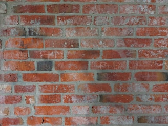Red bricks arranged in a horizontal pattern with visible mortar between each row. The surface shows signs of aging with some discoloration and minor cracks.