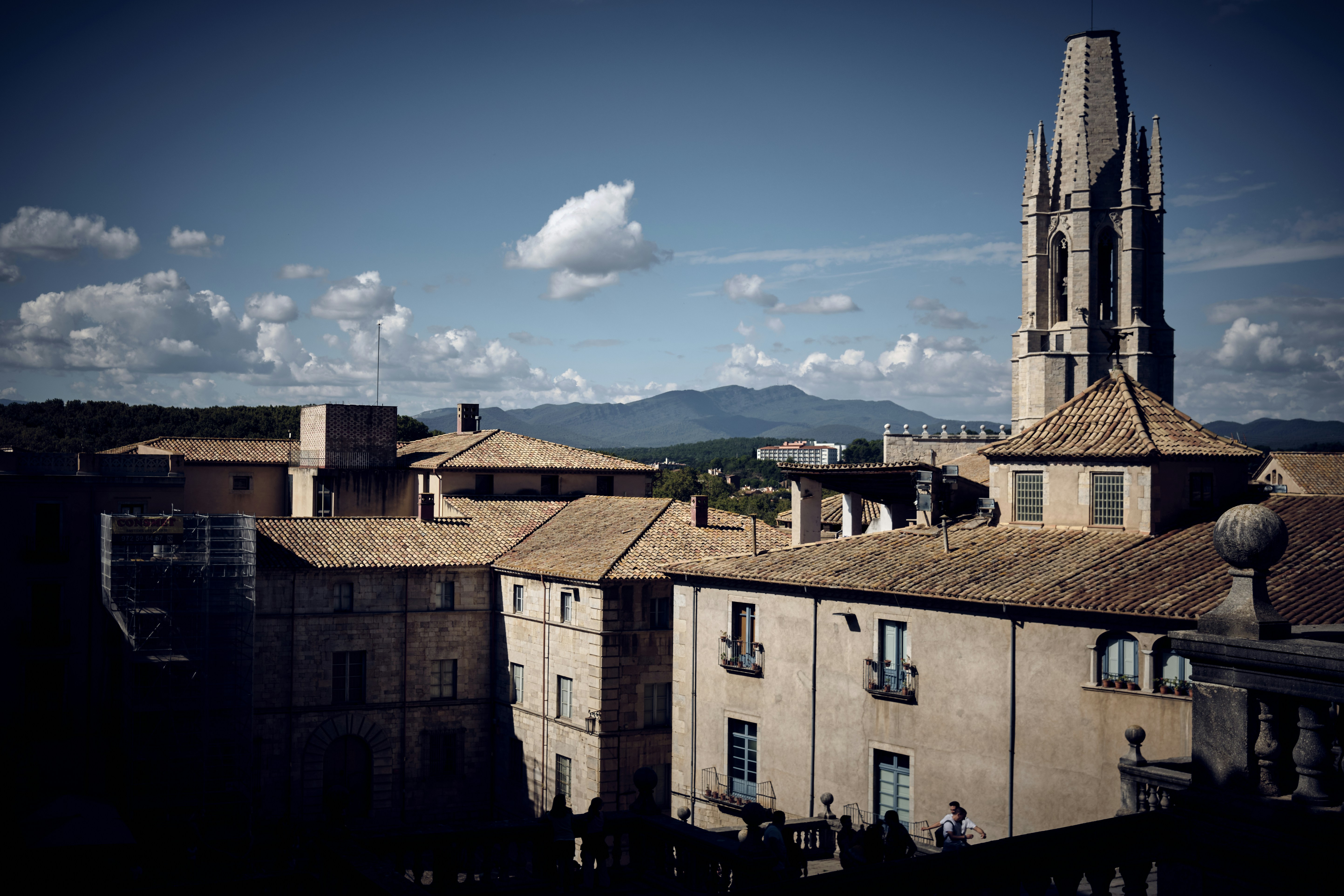 a church tower towering over a city with mountains in the backg…