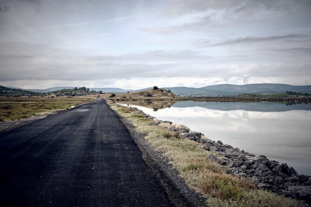 an empty road next to a body of water