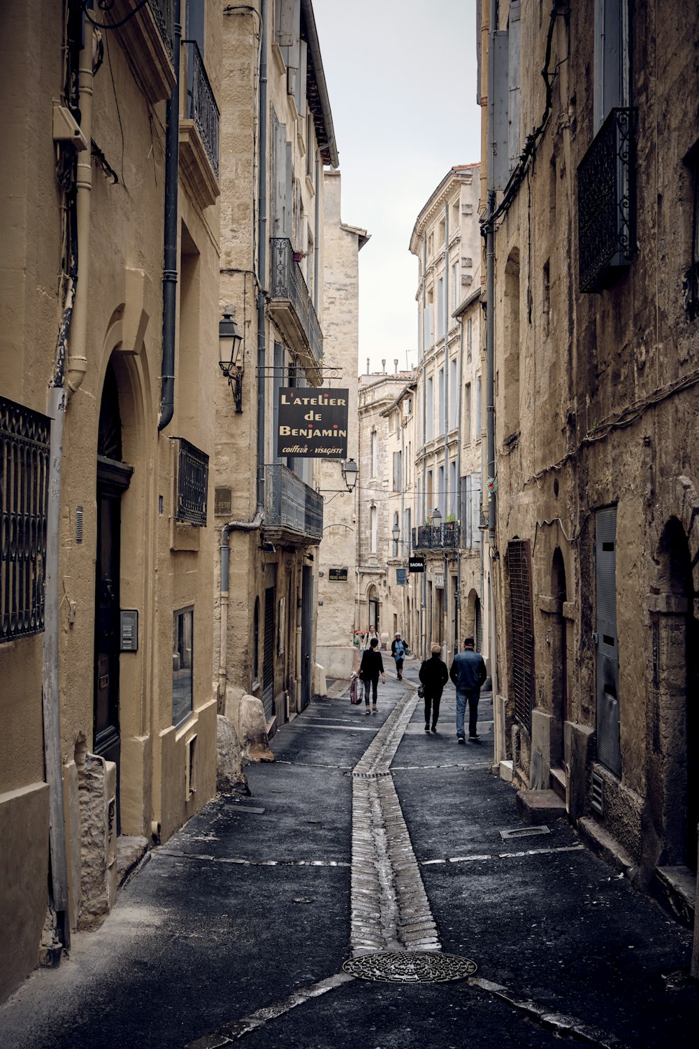 a group of people walking down a street next to tall buildings