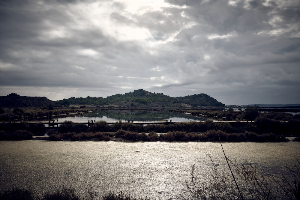 a body of water with a hill in the background