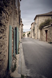 Empty village street with pastel-hued houses under a soft blue sky.