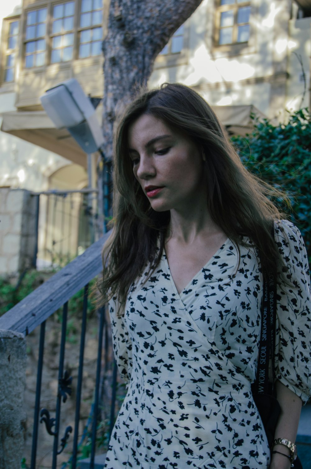 a woman walking down a street next to a tree